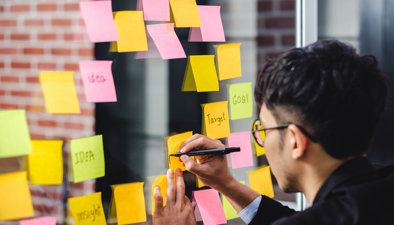 Businessman writing on post-it notes on a board