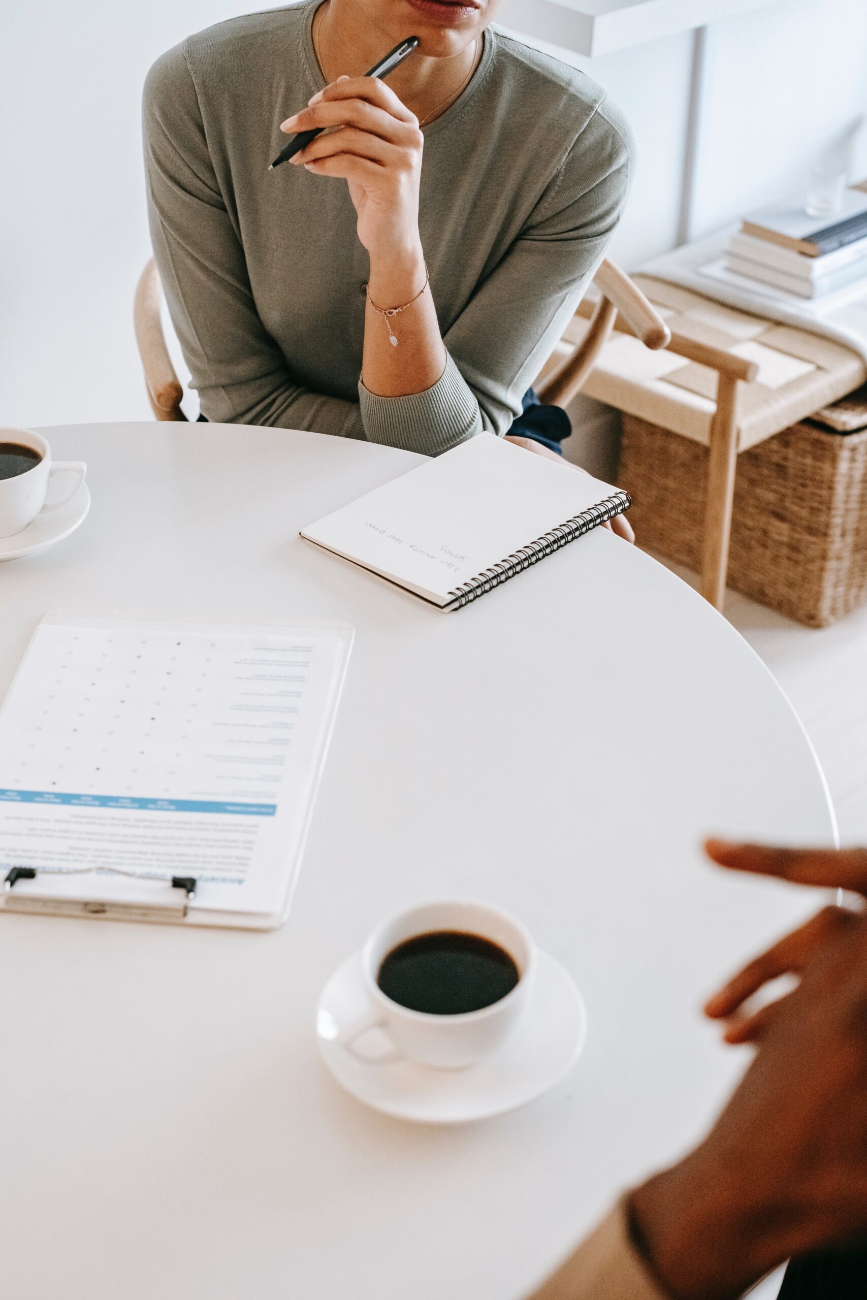 Businesswoman thinking and writing in notebook