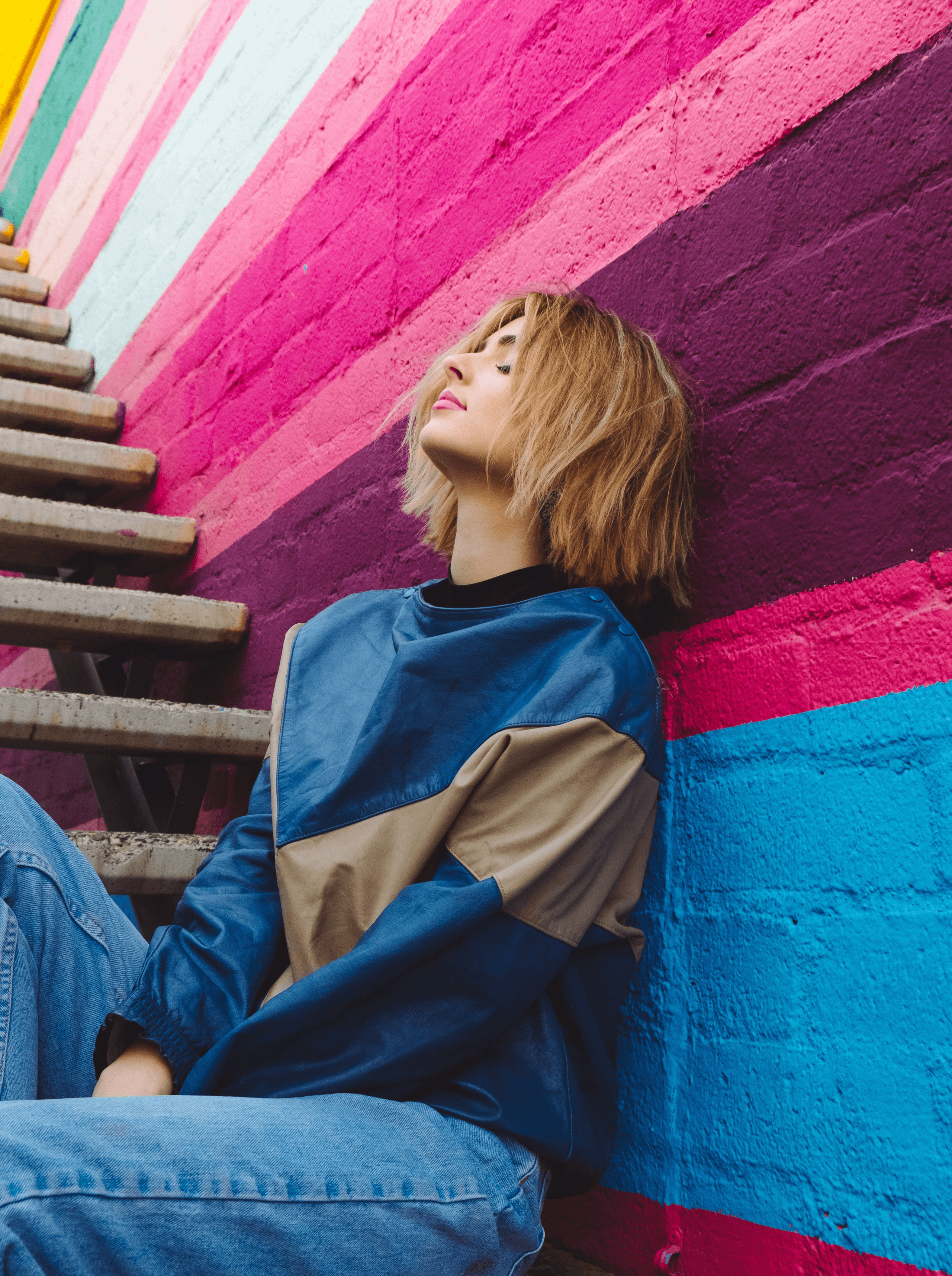 Woman Leaning on Colorful Wall Below The Stairs