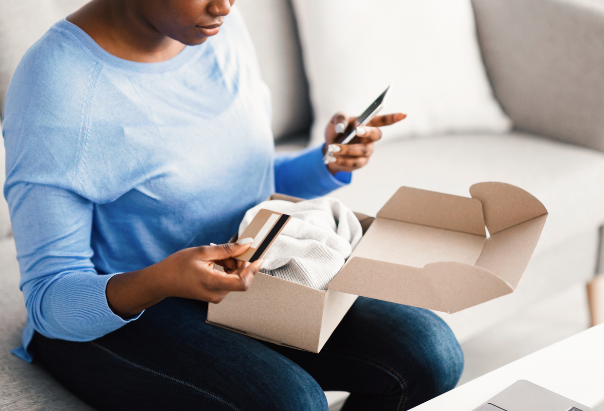 Woman holding mobile phone and credit card on her couch