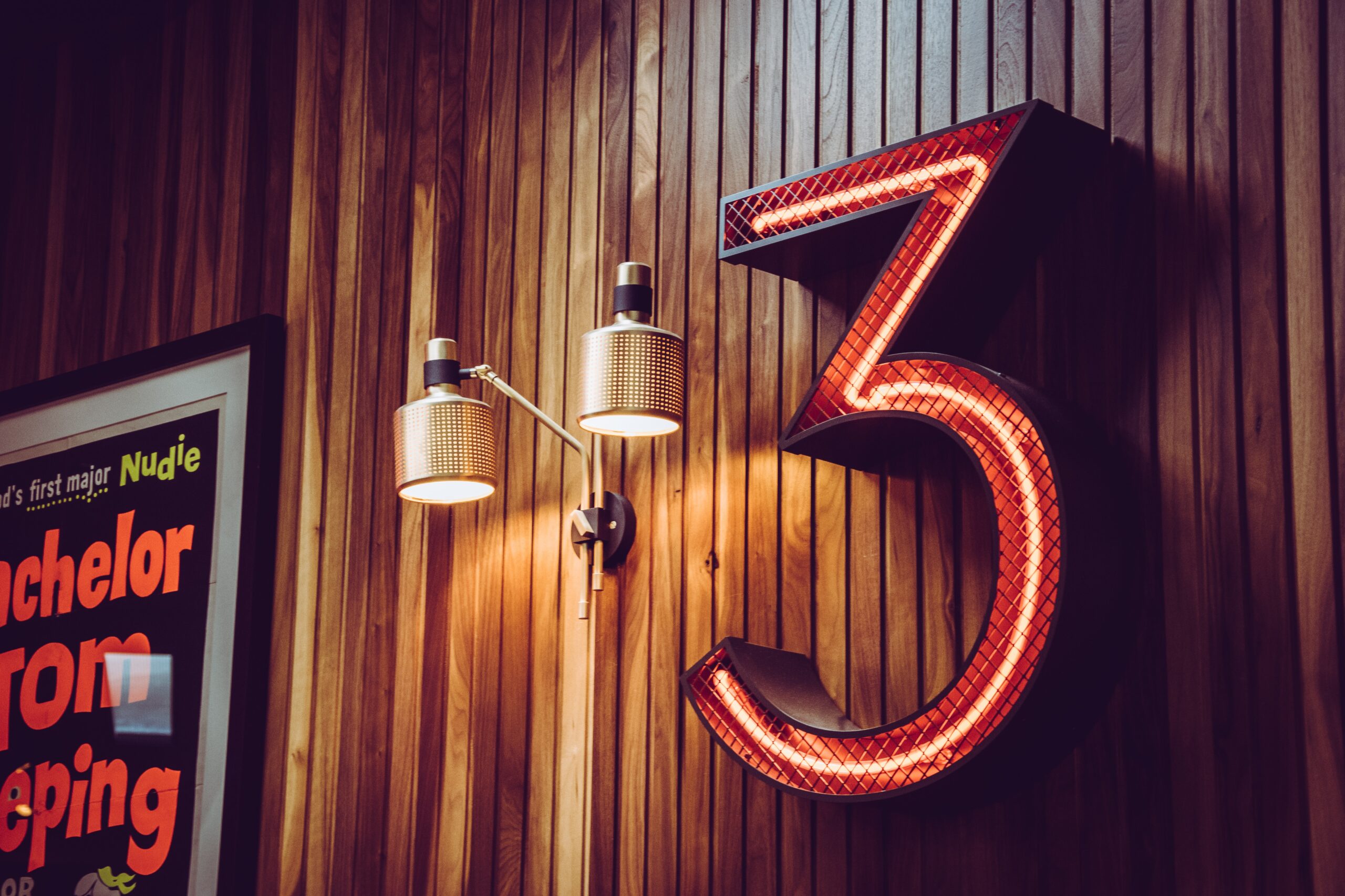 Glowing neon sign of the number 3 on a wall