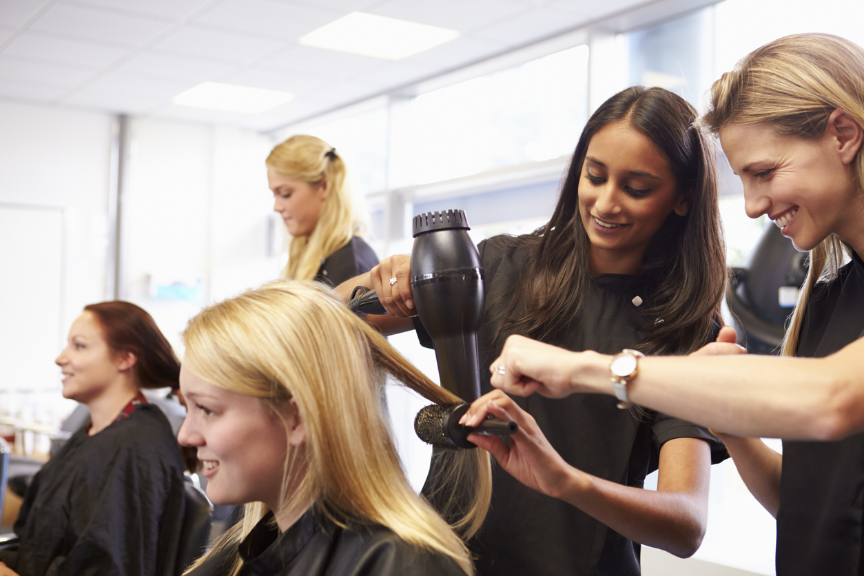 Two hairdressers blow drying a customer's hair