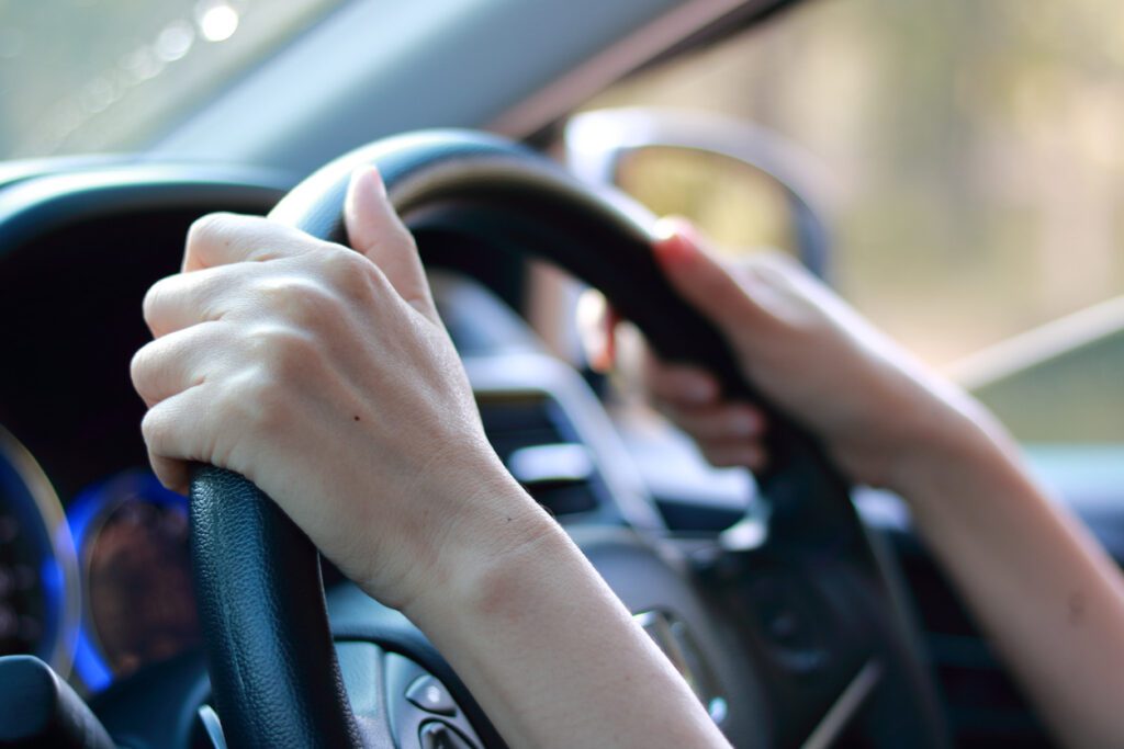 Hand of Woman on Steering Wheel of Her Car